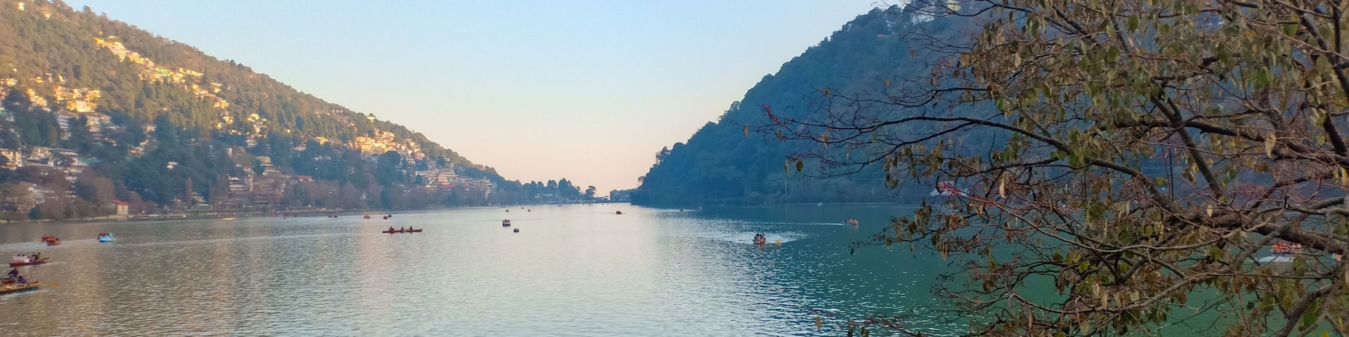 A calm river with boats, surrounded by hills and sparse trees.