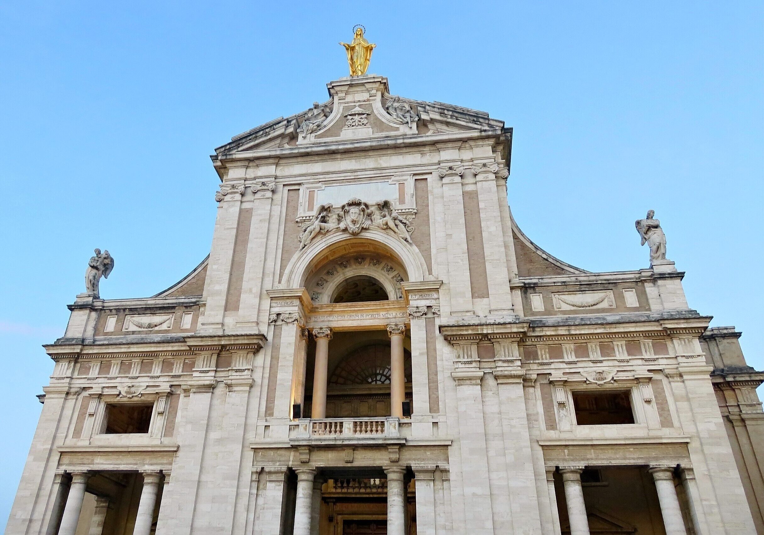 A grand neoclassical building with ornate sculptures and a golden statue on top.