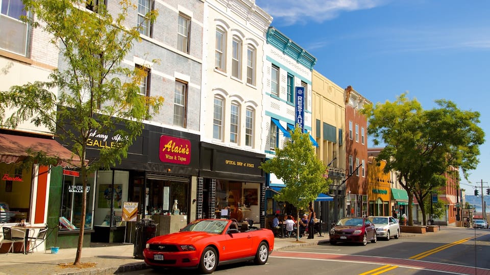 A street lined with various shops, including a wine and tapas restaurant, and a red convertible parked on the side.