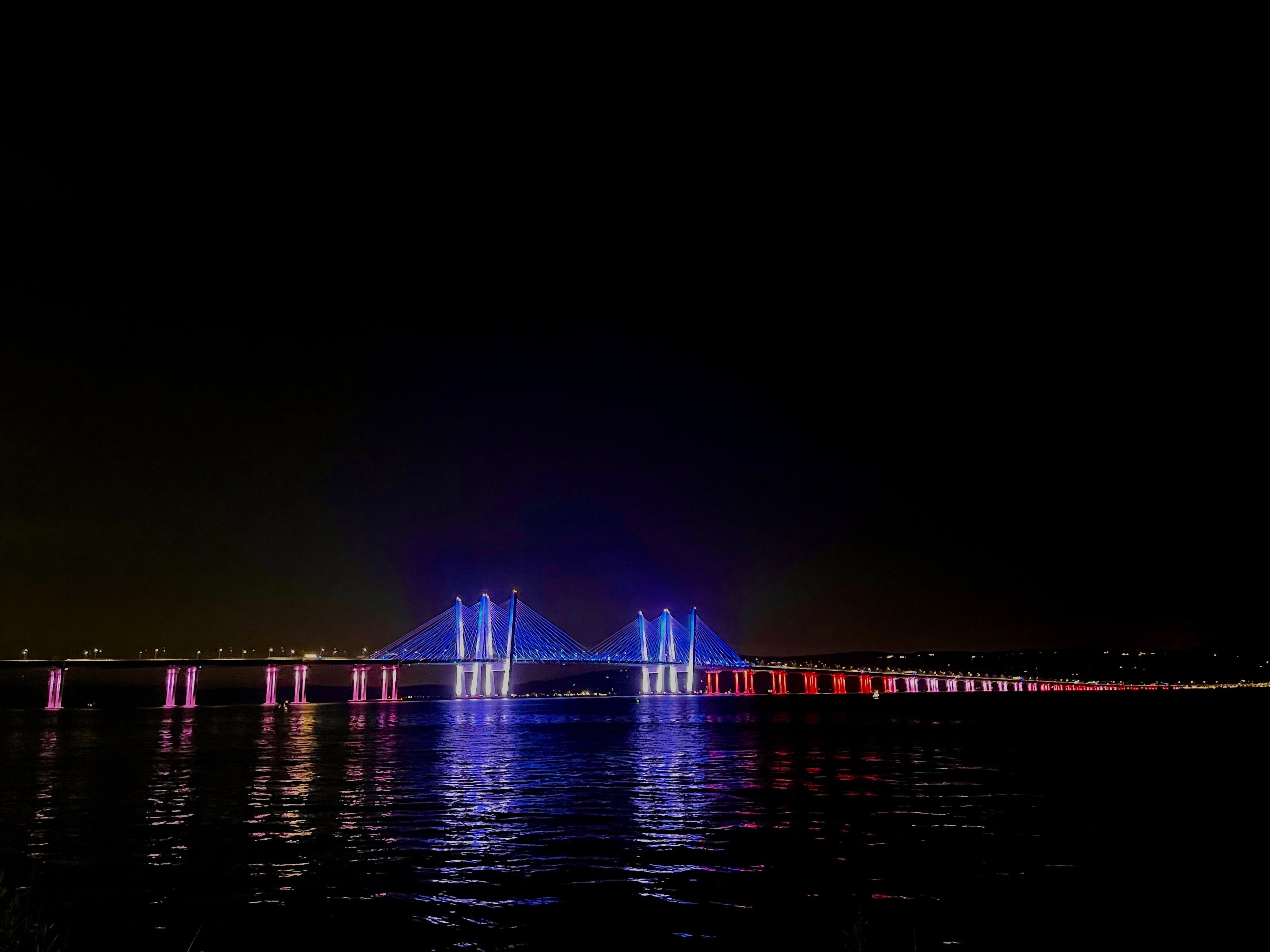 Un puente iluminado con luces azules y rojas durante la noche.