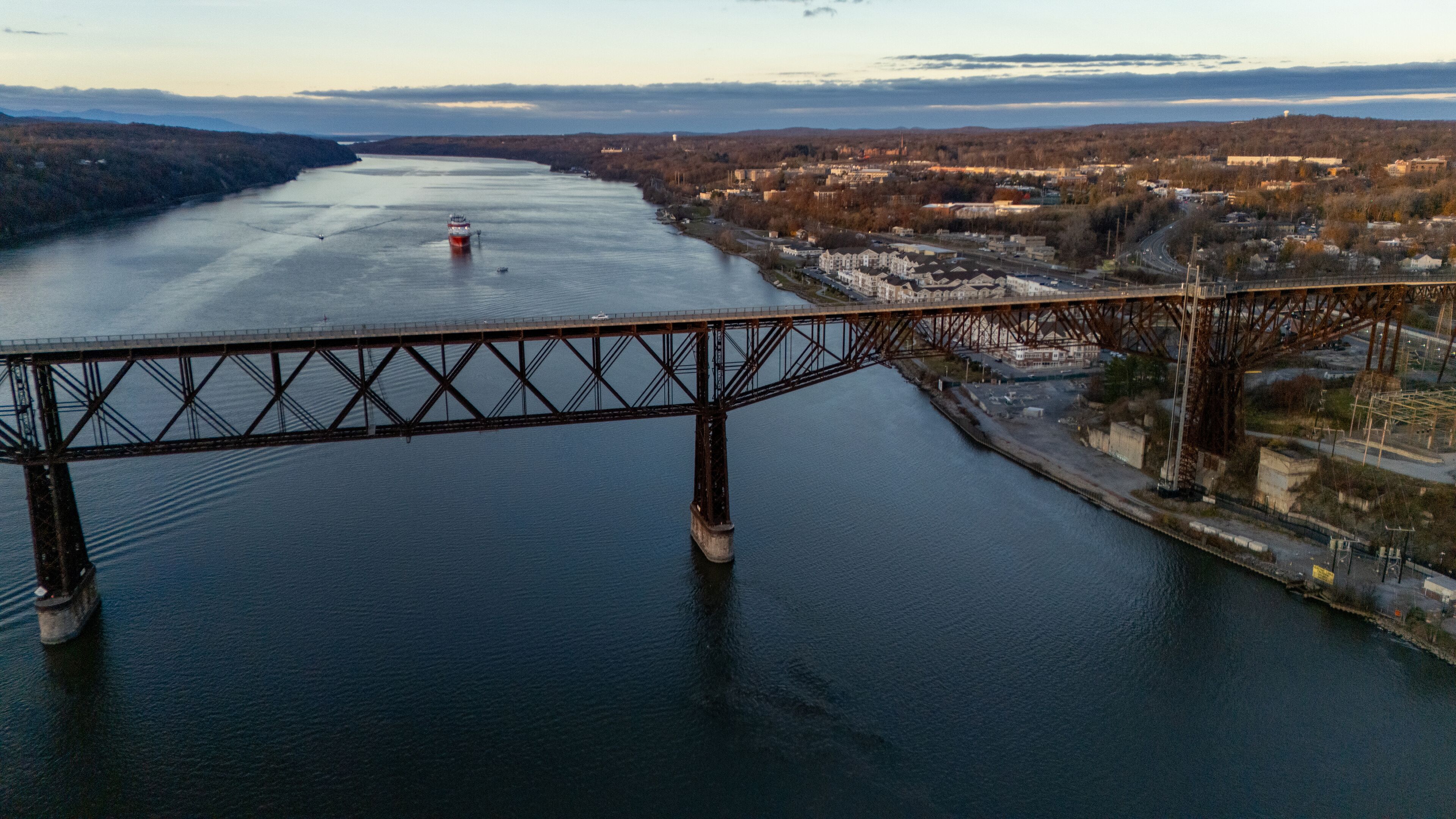 Aerial view of the majestic Mid-Hudson Bridge stretches across the tranquil Hudson River under a fading sunset, Poughkeepsie, New York, United States.