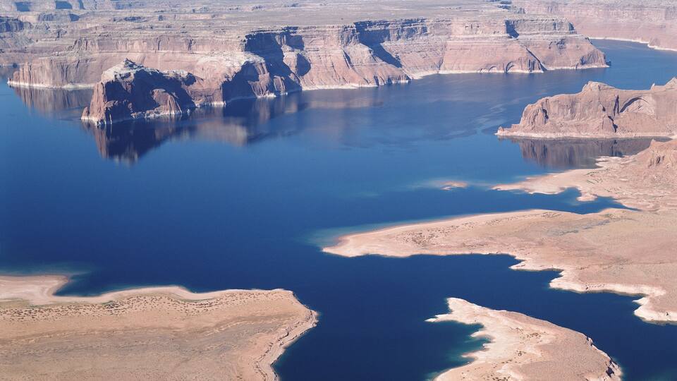 A vast canyon with a large body of water reflecting the sky.