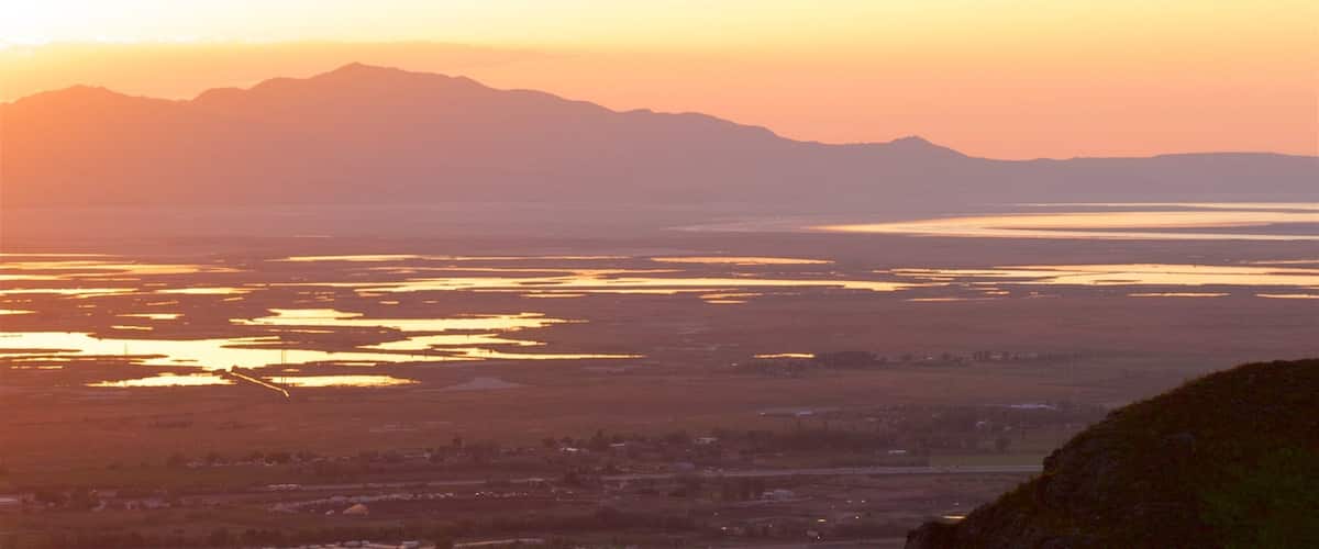 A sunset over a valley with mountains in the background.