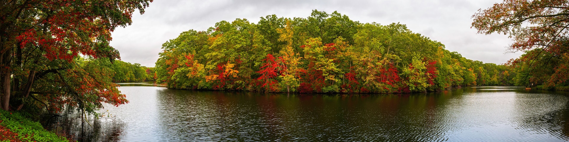 A calm lake surrounded by trees with autumn foliage.