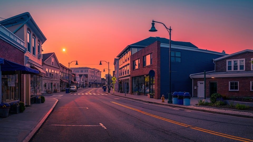 A sunset over a street lined with brick buildings and storefronts.