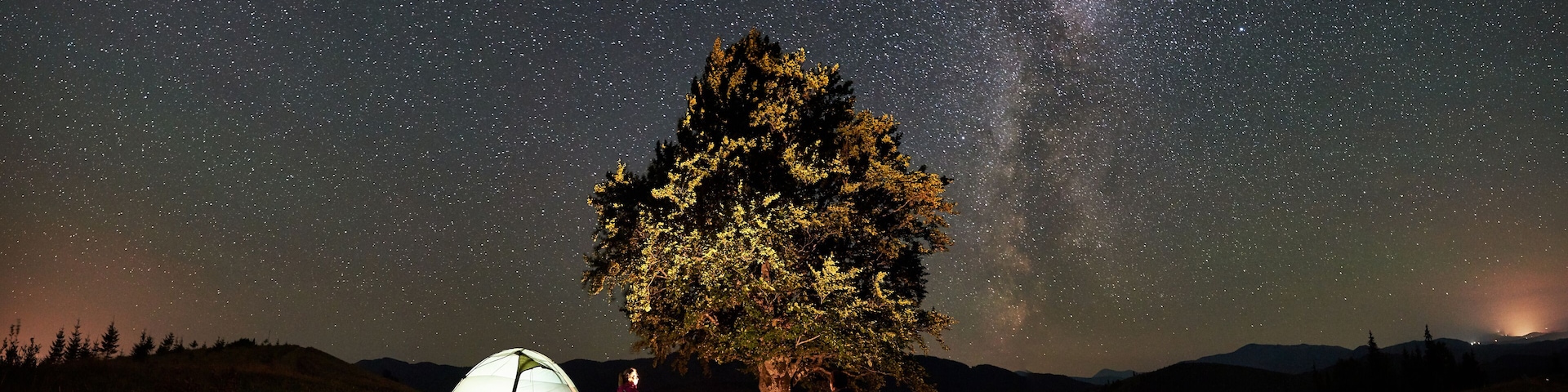 A night scene with a tent, a tree, and a starry sky.