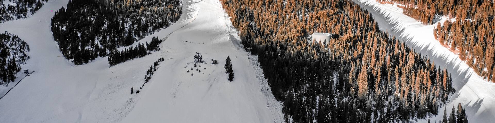 A snow-covered mountain with a ski lift and forested slopes.