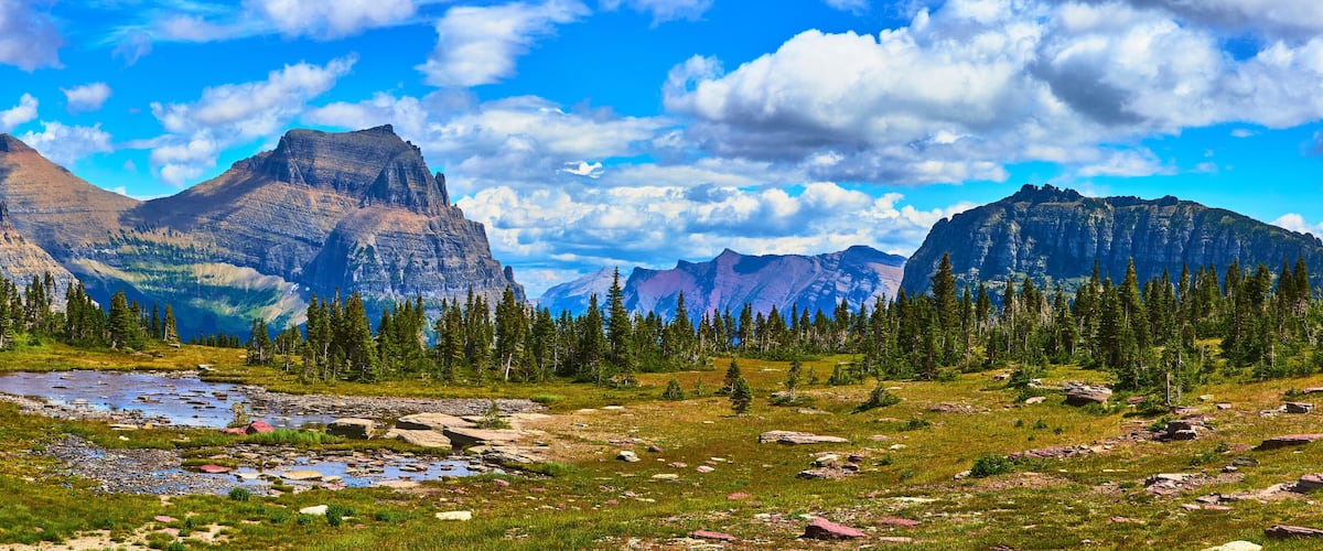 A mountainous landscape with a river, dense forests, and rocky terrain.