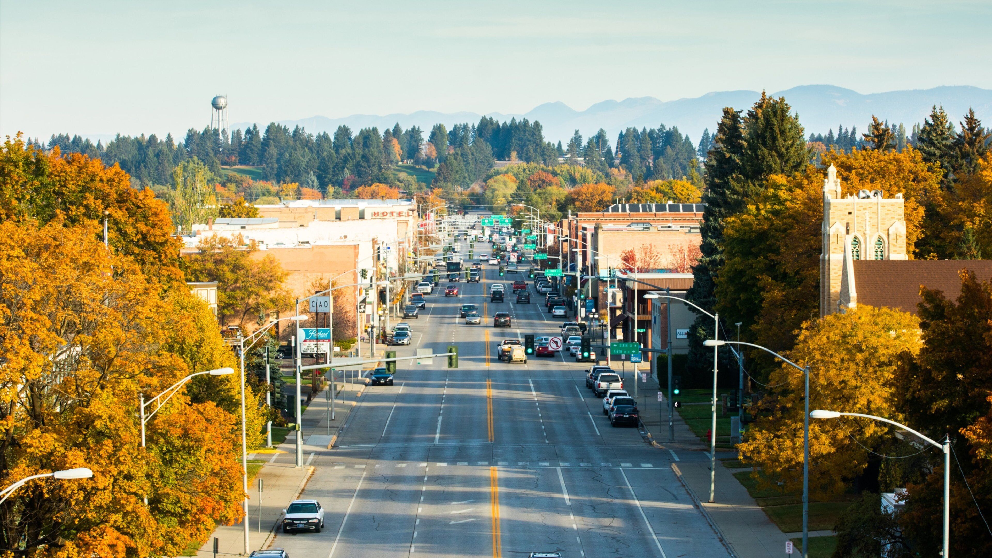 A city street with autumn foliage, a water tower, and a church.
