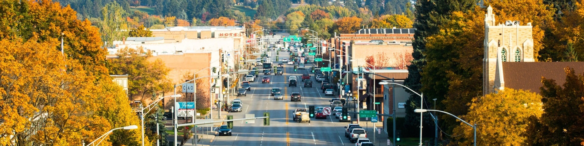 A city street with autumn foliage, a water tower, and a church.