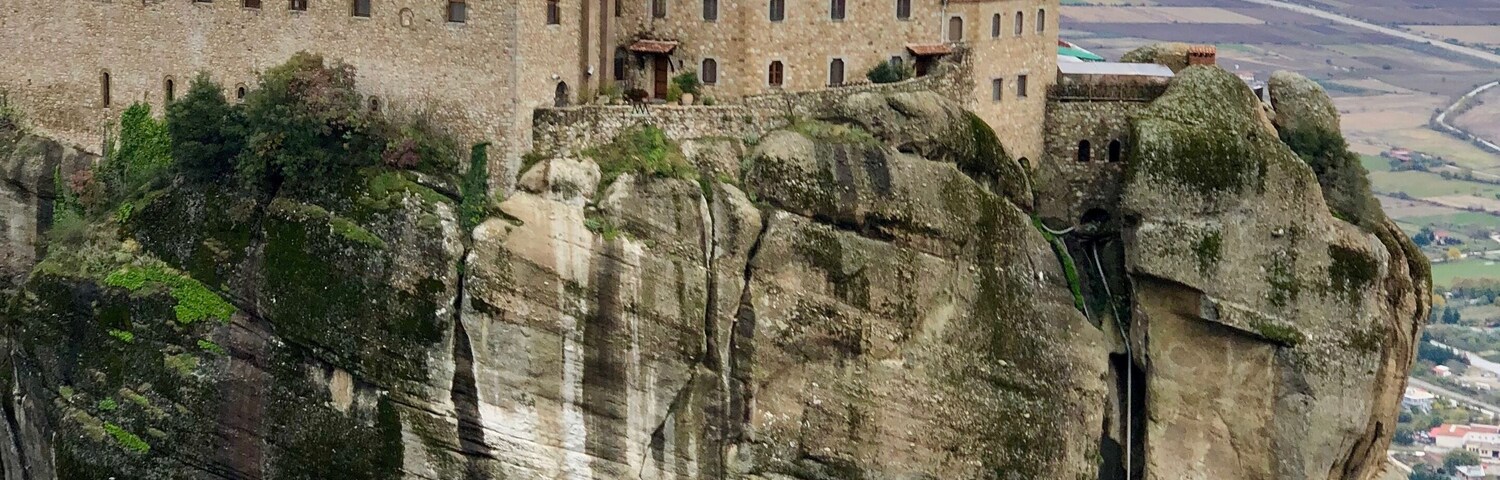 Um edifício histórico empoleirado no topo de um penhasco rochoso, com vista panorâmica da paisagem.