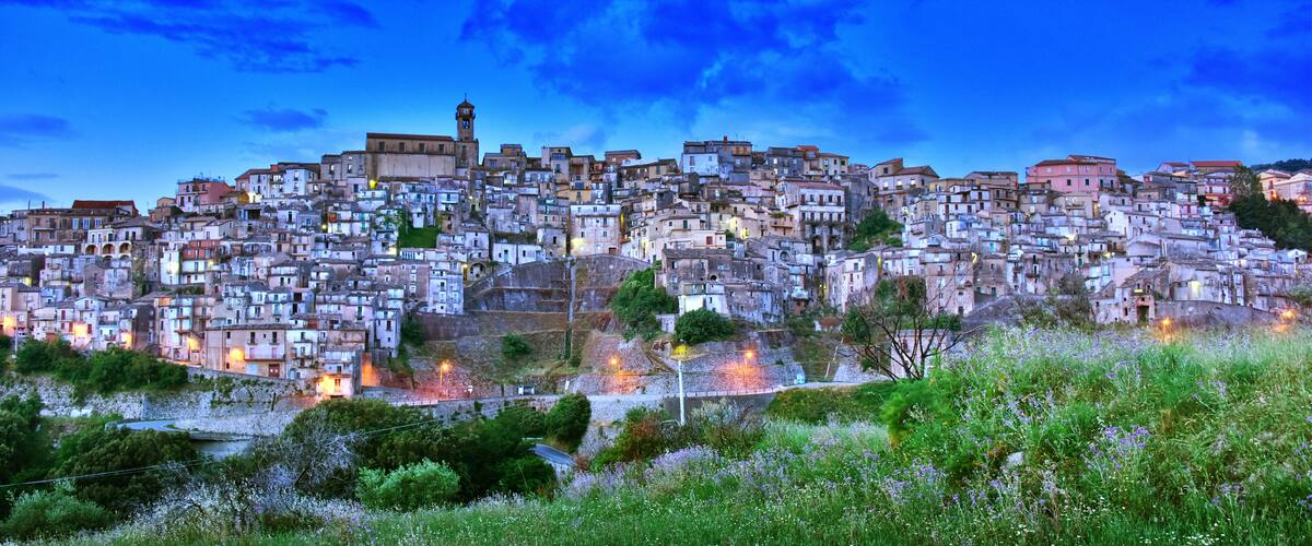 A densely packed hillside town with historic buildings and a prominent tower.