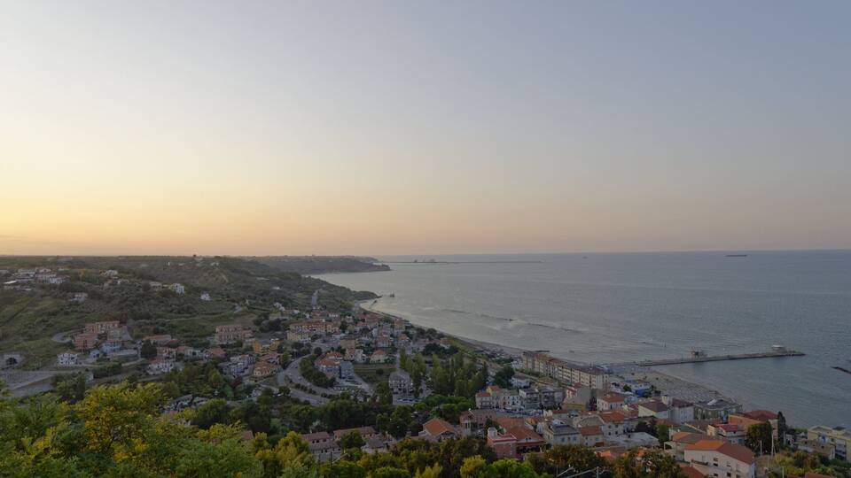 A coastal town with a bridge, buildings, and a beach.