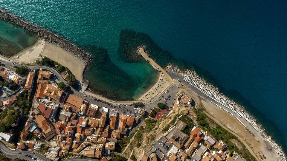 A coastal town with a winding road, a beach, and a rocky shoreline.