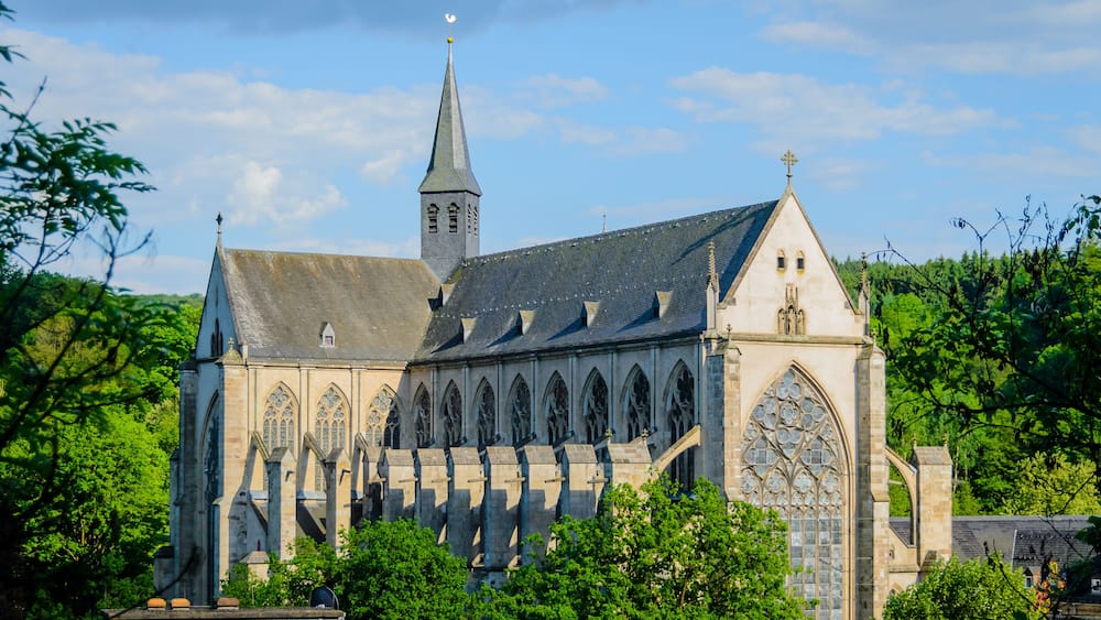 A historic church with a tall spire, large arched windows, and a stone facade.