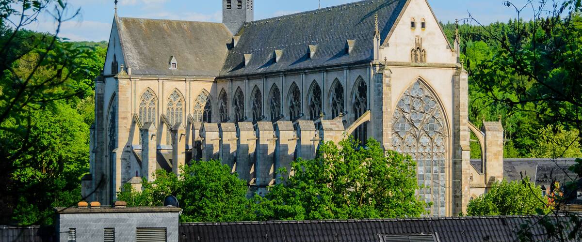 A historic church with a tall spire, large arched windows, and a stone facade.