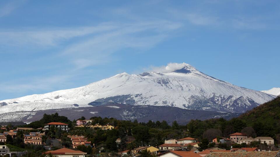 A snow-capped mountain with a village at its base.