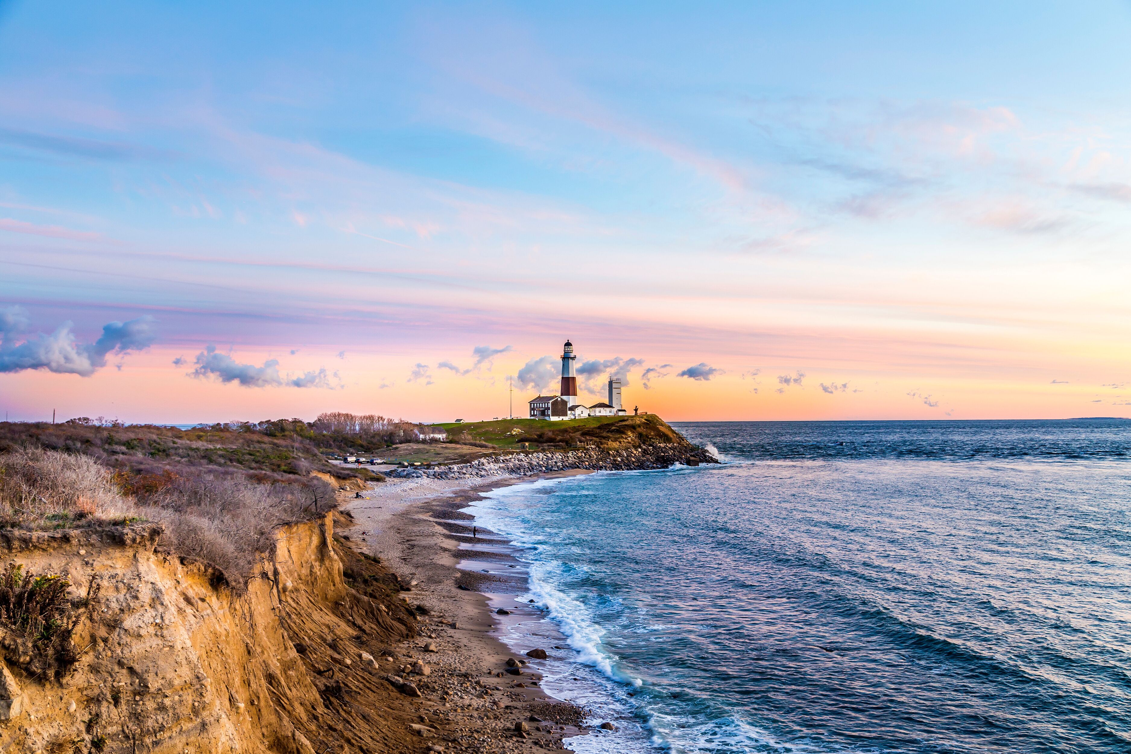 Um farol em um penhasco à beira-mar ao pôr do sol.