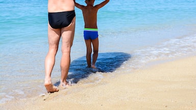 Man and boy carry a rubber boat on sunny Vrachos beach, Parga, Greece.