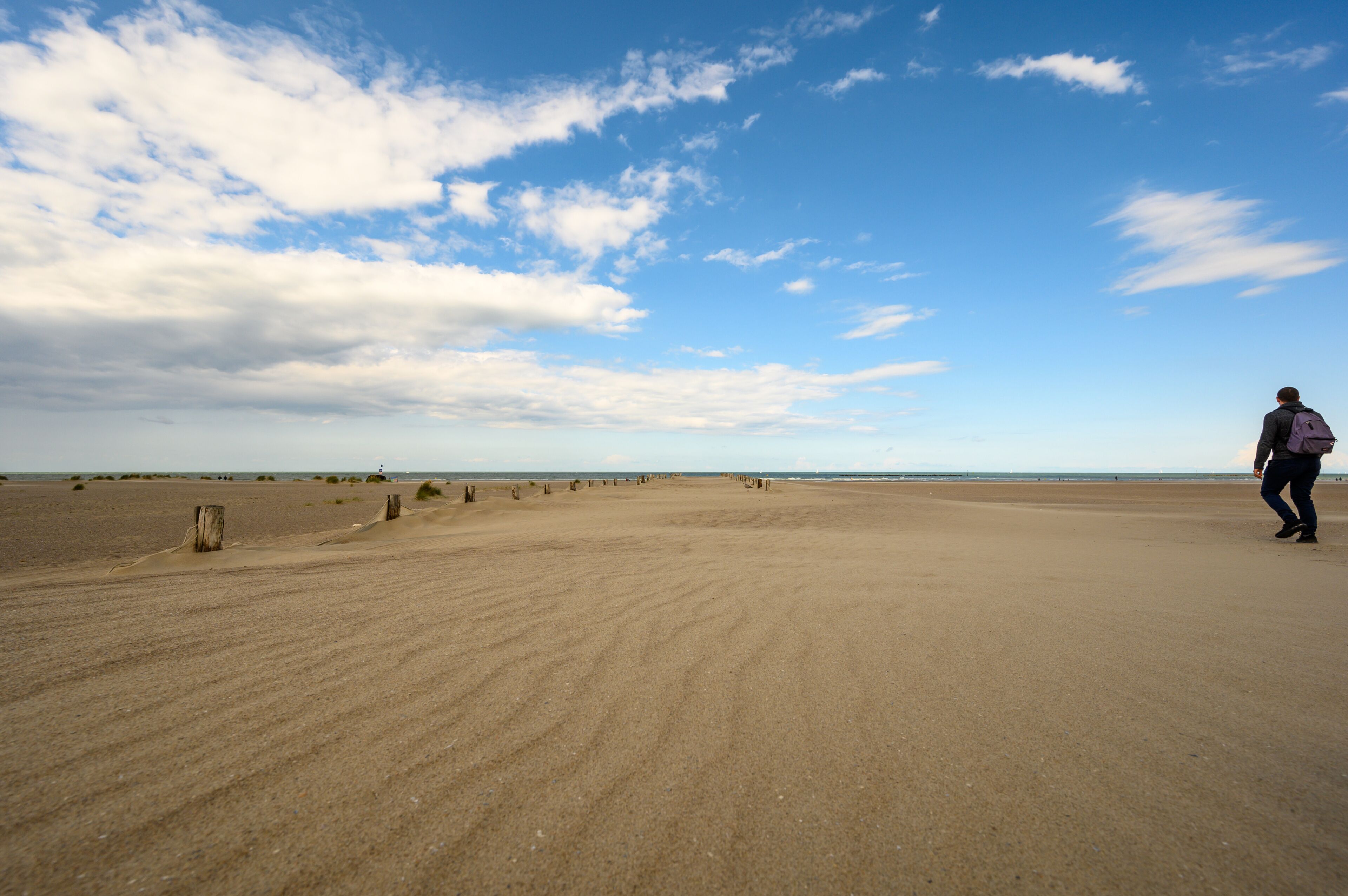 Backpacker walks along beach at Dunkirk