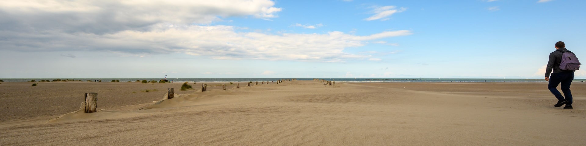 Backpacker walks along beach at Dunkirk
