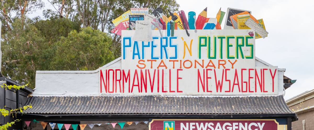 A stationary news agency with a colorful signboard and various advertisements.