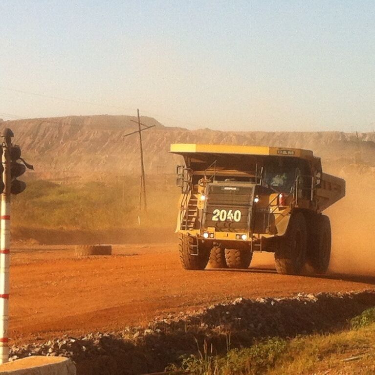 A large dump truck with the number 2040 on its front driving on a dirt road.