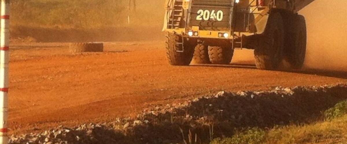 A large dump truck with the number 2040 on its front driving on a dirt road.