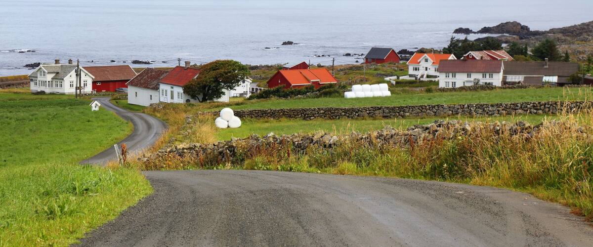 A coastal village with houses, a winding road, and a body of water.