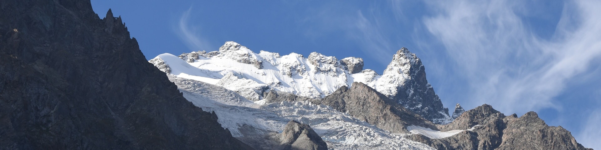 Una cordillera nevada con picos escarpados y un cielo azul despejado.