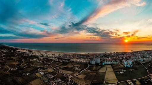 Aerial panoramic view of Costa Da Caparica, Portugal in sunset. Coastline of glorious sandy beaches and powerful Atlantic ocean waves.