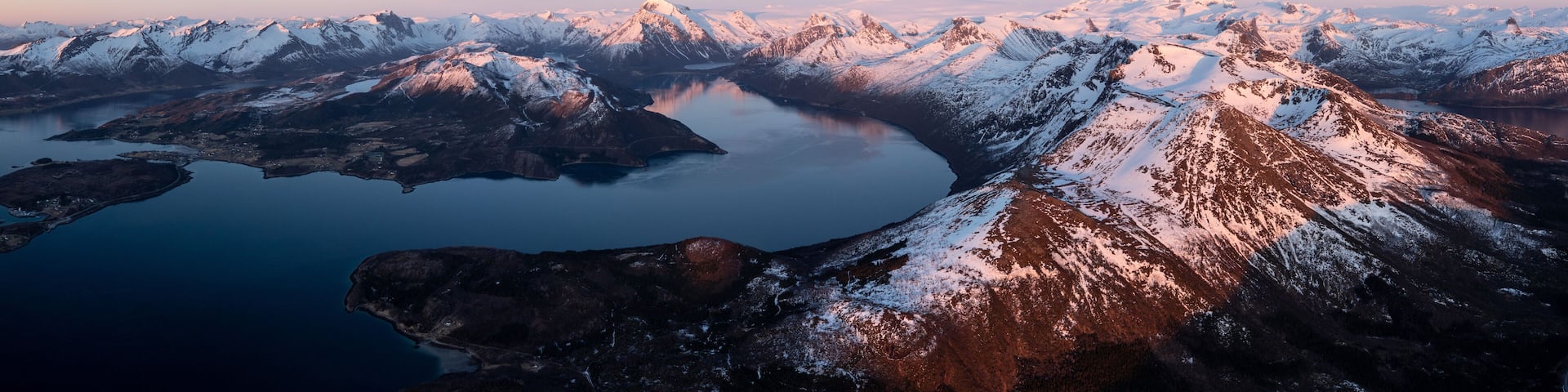 A snow-covered mountain range with a lake at its base.