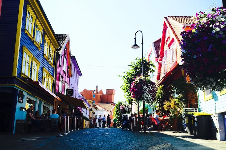 A cobblestone street lined with colorful buildings and hanging flower baskets.