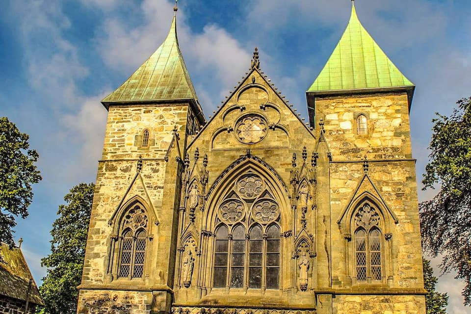 Una església històrica amb dues torres de teulades verdes i una ornamentació de pedra detallada.