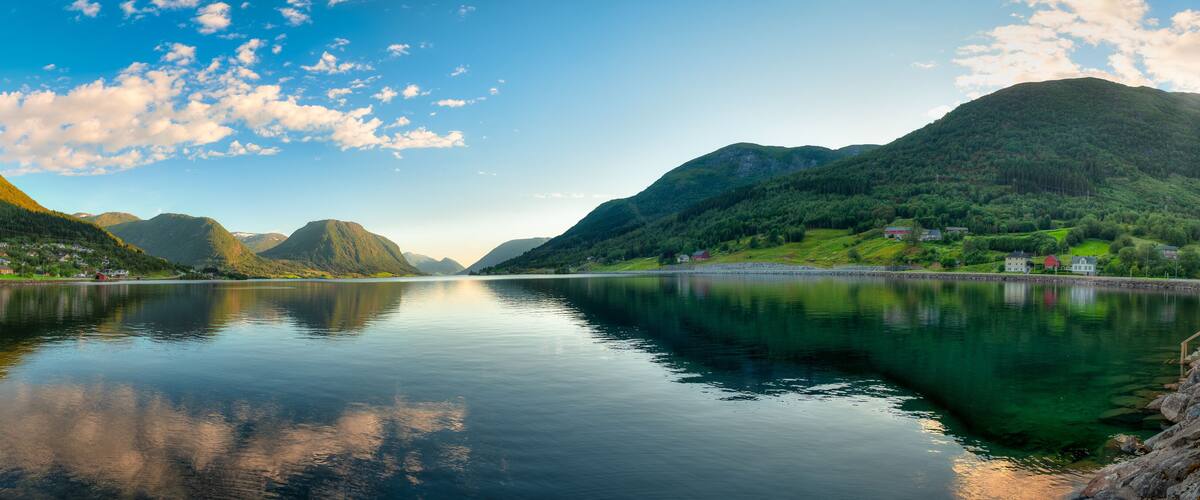 A calm lake surrounded by mountains and houses.