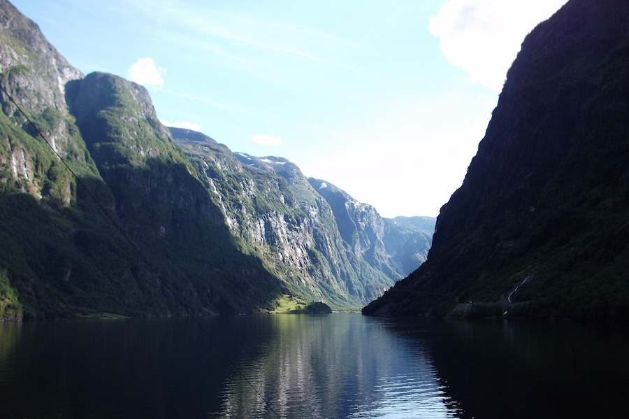 A narrow fjord flanked by steep, green-covered cliffs.