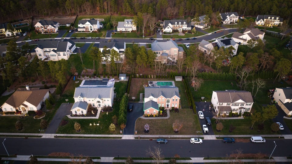 A suburban neighborhood with multiple houses, a main road, and a large green space.