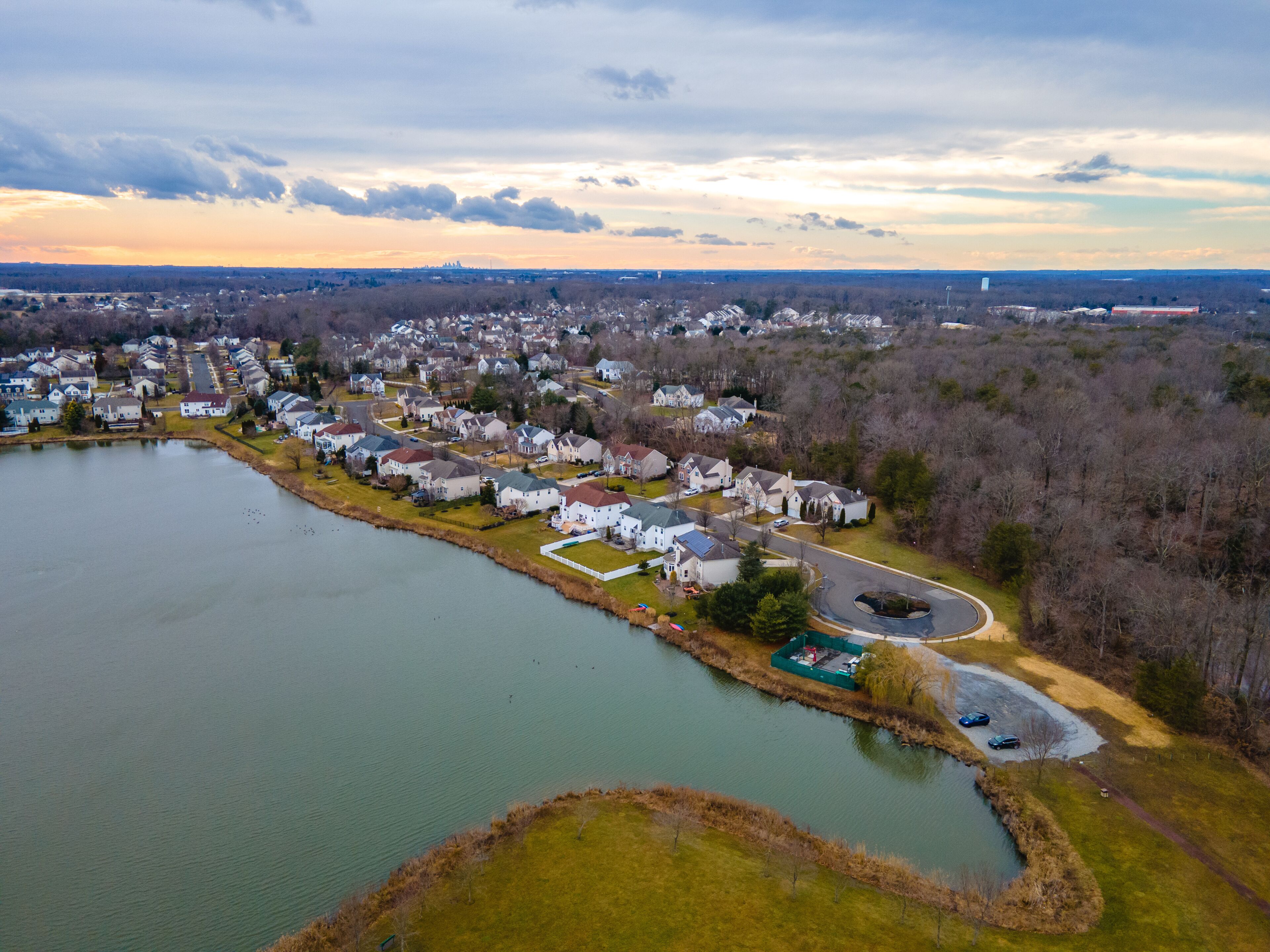 A lakeside residential area with houses, a small dock, and a clear sky.