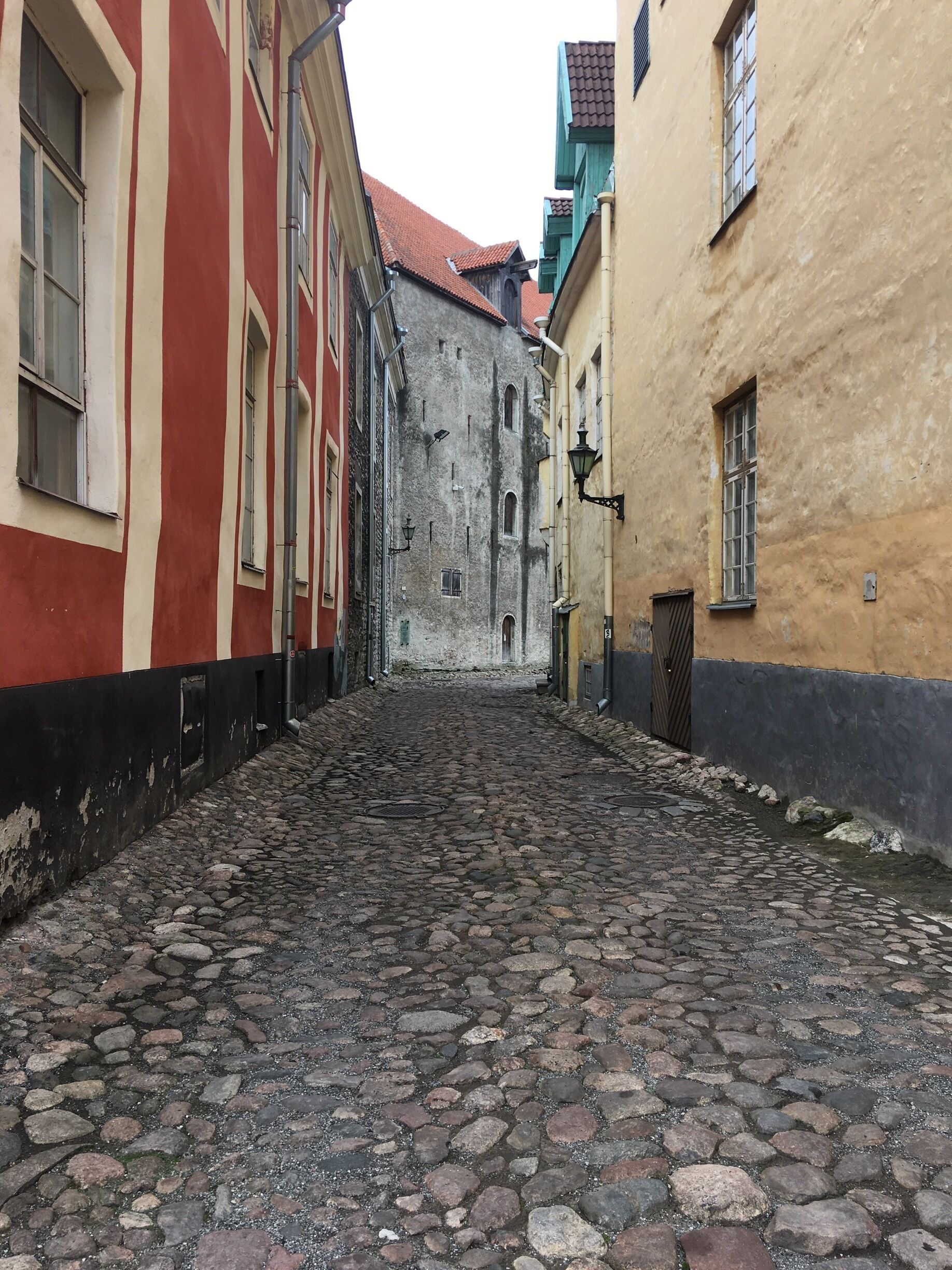 Calle adoquinada flanqueada por edificios históricos con fachadas rojas y amarillas.