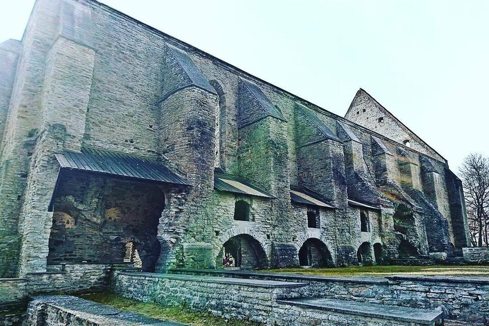 A large, historic stone building with multiple arched windows and a steeply pitched roof.