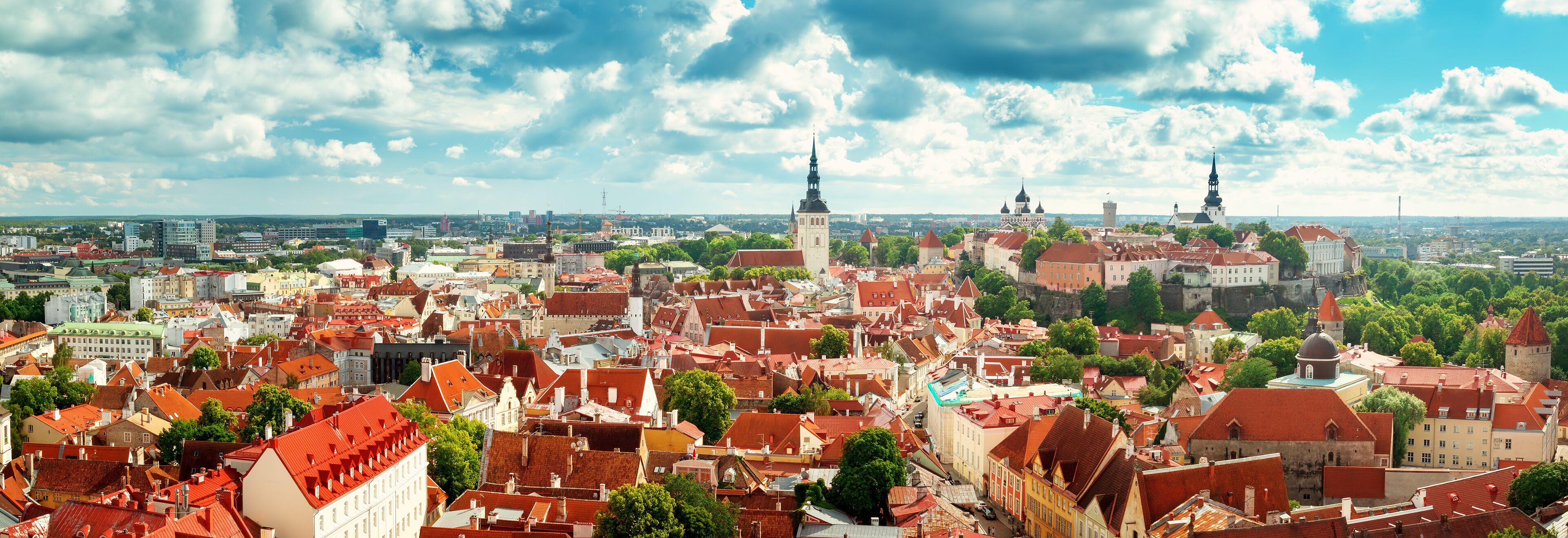 A cityscape with historic buildings, red-roofed structures, and prominent towers.