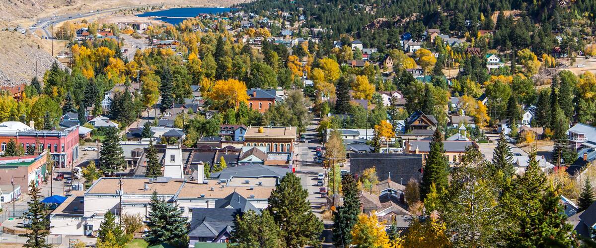 A town nestled in a valley with autumn foliage, surrounded by mountains and a lake.