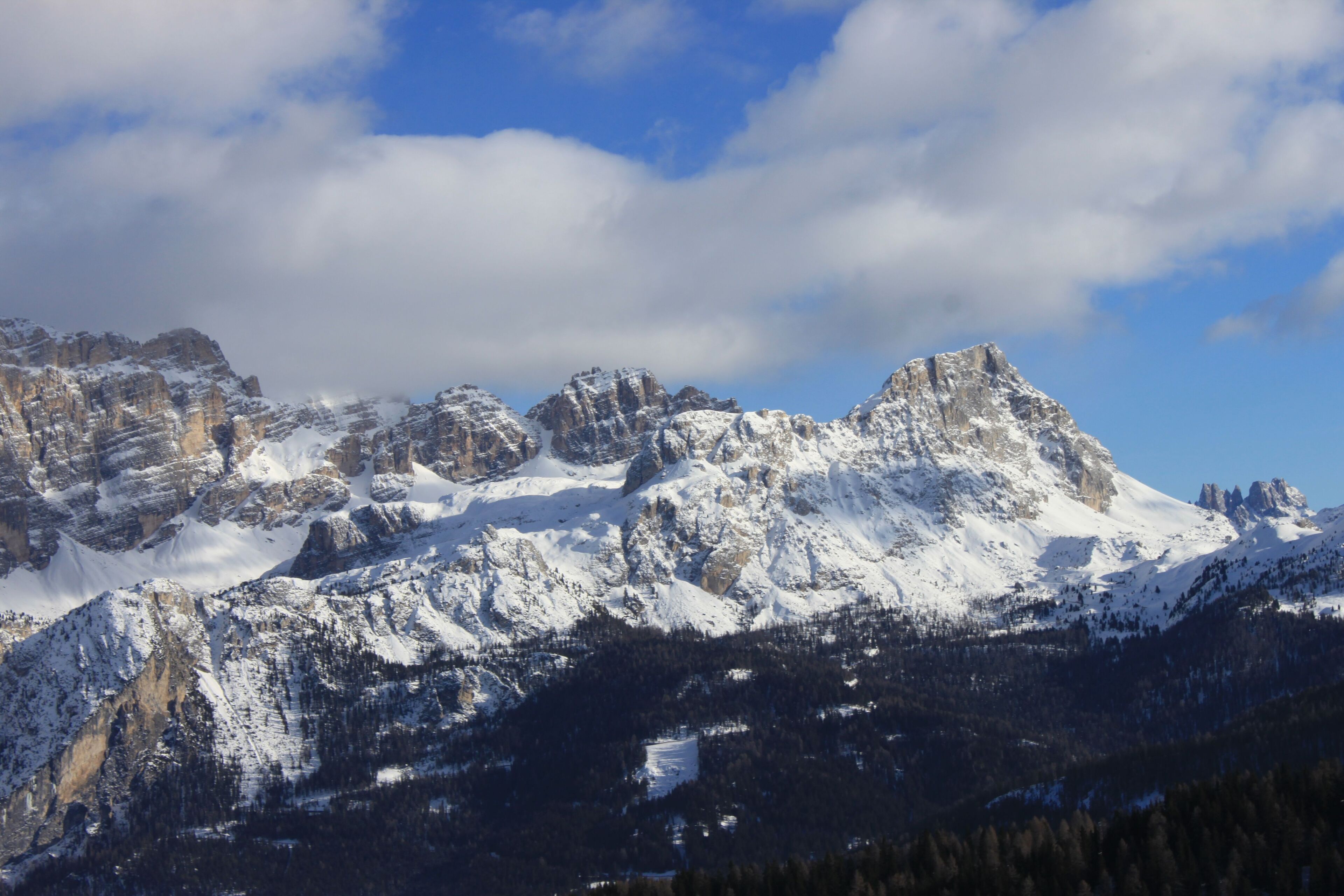 A snow-covered mountain range with rugged peaks and a clear blue sky.