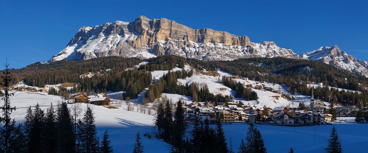 A snow-covered mountain range with a village nestled at its base.