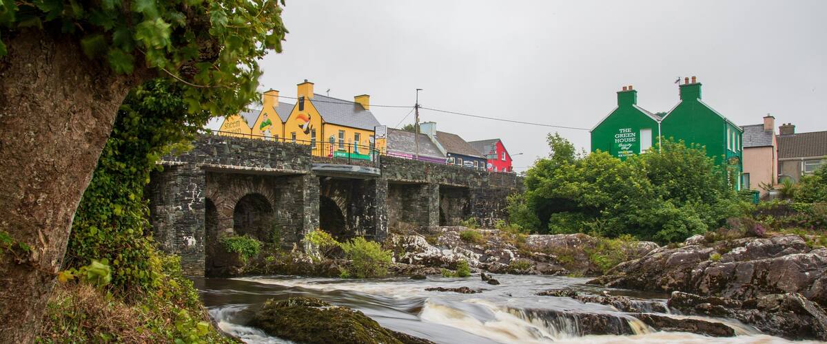 A river flowing through a town with historic stone bridges and colorful buildings.