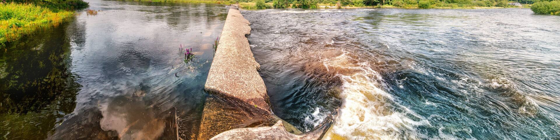 Panoramic view of concrete dam on river Lee in Ballincollig Regional park in summer on cloudy day