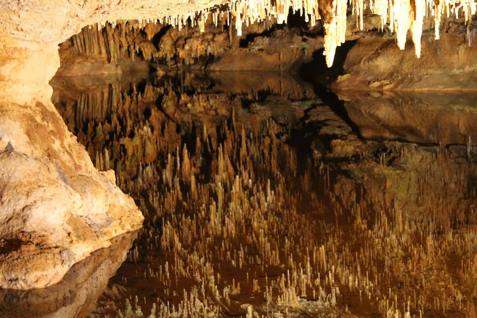A cave with stalactites hanging from the ceiling and stalagmites rising from the ground.