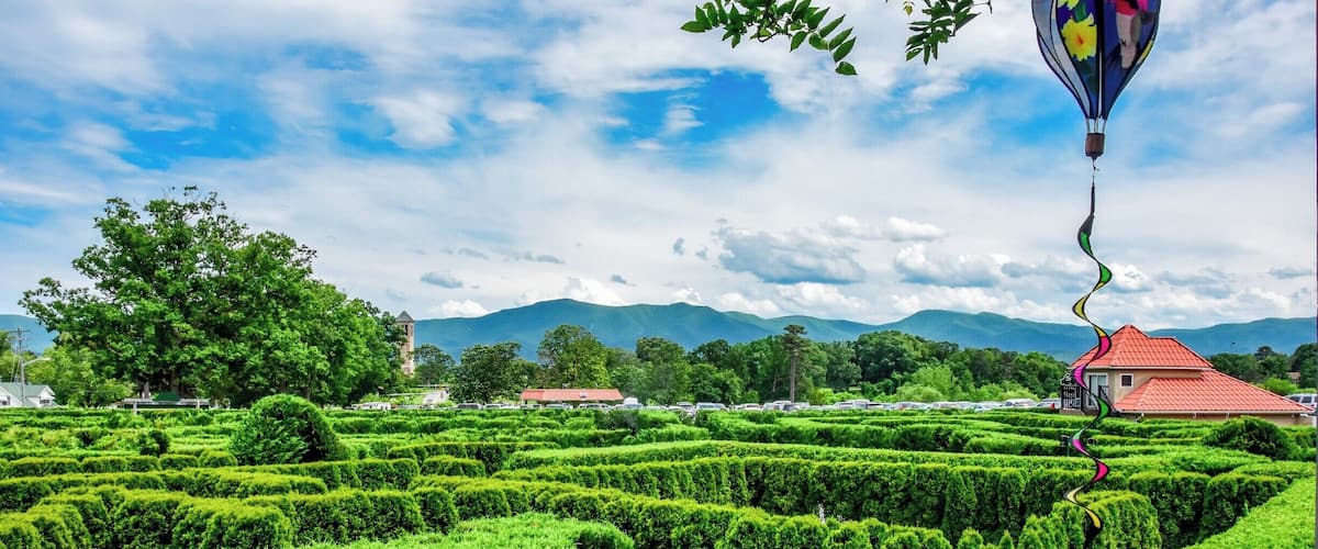 Eight foot tall hedges creating a pathway of puzzlement, misting fog, and endless confusion! Travel past fountains, through hidden tunnels, and over a lookout tower. 
Navigate your way through twists and turns while searching for hidden goals on a mission to discover the secret of the maze.
Unravel the mystery of the largest hedge maze in the Mid-Atlantic states - a one acre ornamental garden at Luray Caverns.
It is a fun filled activity for people of all age groups. The Garden of Maze is right next to the Luray Caverns. So if you plan a trip to see Luray Caverns, you can visit the maze too. Just let loose, get lost and be found at the maze ;)
Tip: The view from the lookout tower is beautiful like this one. Just sit back, take in the beauty and relax here. Also, its fun to see people getting lost in the maze ;P