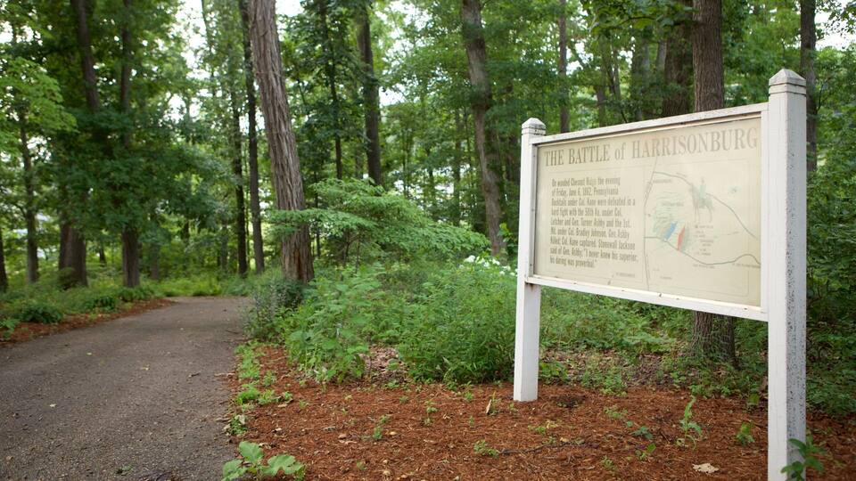 A historical marker titled "The Battle of Harrisburg" in a wooded area with a dirt path.