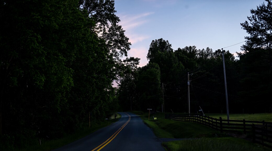 Countryside rural paved road in Lyndhurst, Virginia at evening dark night sunset with fence at Longstaff lane and Reeds gap road in mountains